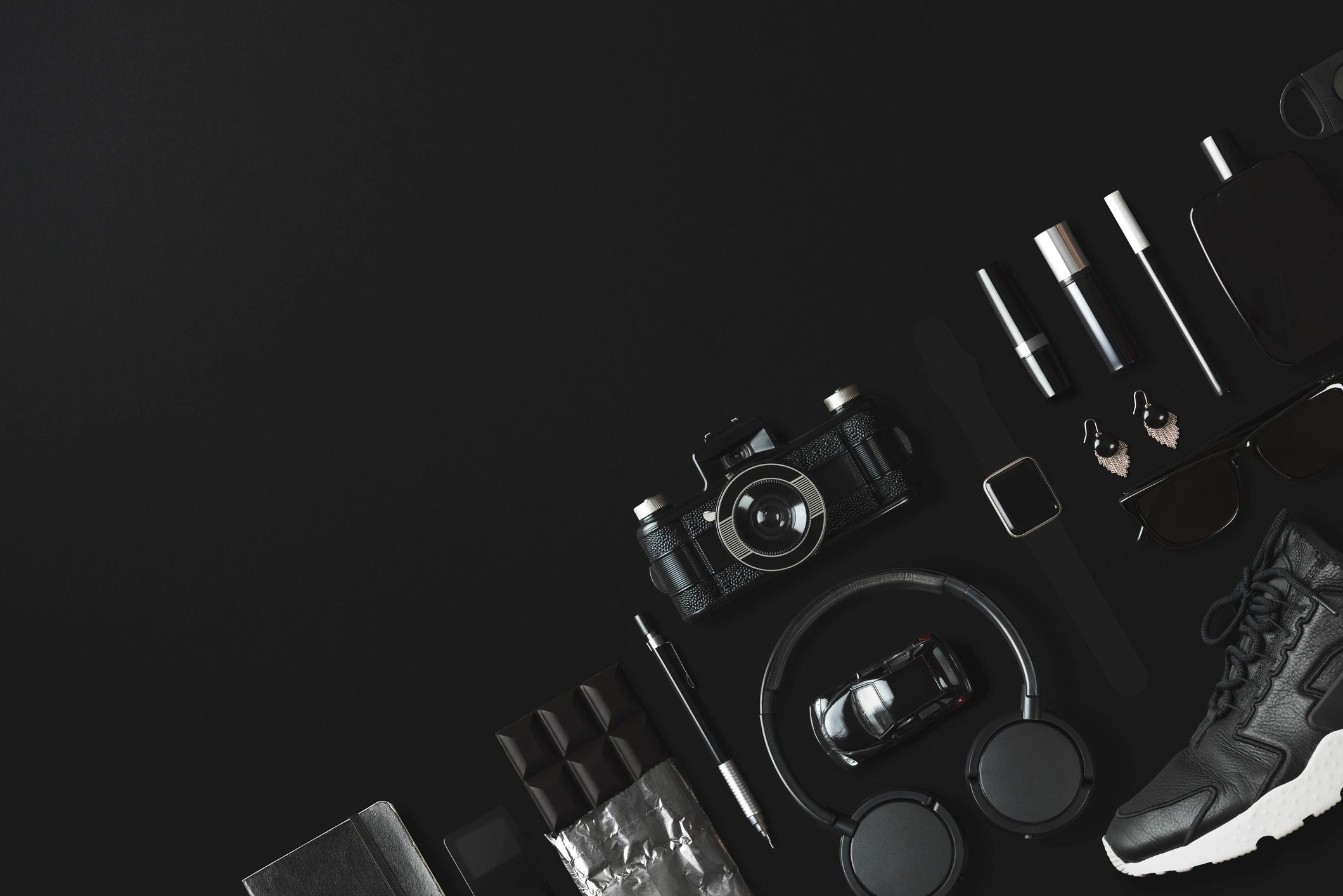 Black fashion items flat lay on a black background